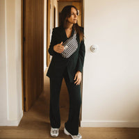 Thumbnail for Woman standing in a doorway wearing a black suit and white sneakers.