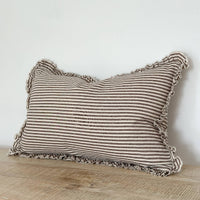 Thumbnail for Striped pillow with ruffled edges on a wooden surface against a white wall