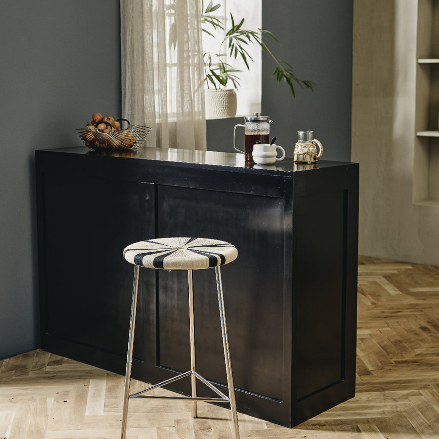 Black bar cabinet with a stool in a room with a window and plant