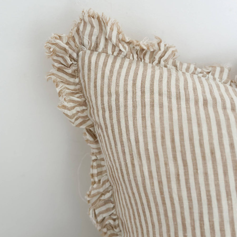 Striped linen pillow with ruffled edges on a white background