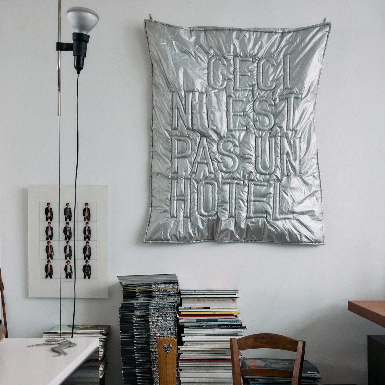Room interior with a metallic poster, books, and wooden chairs.