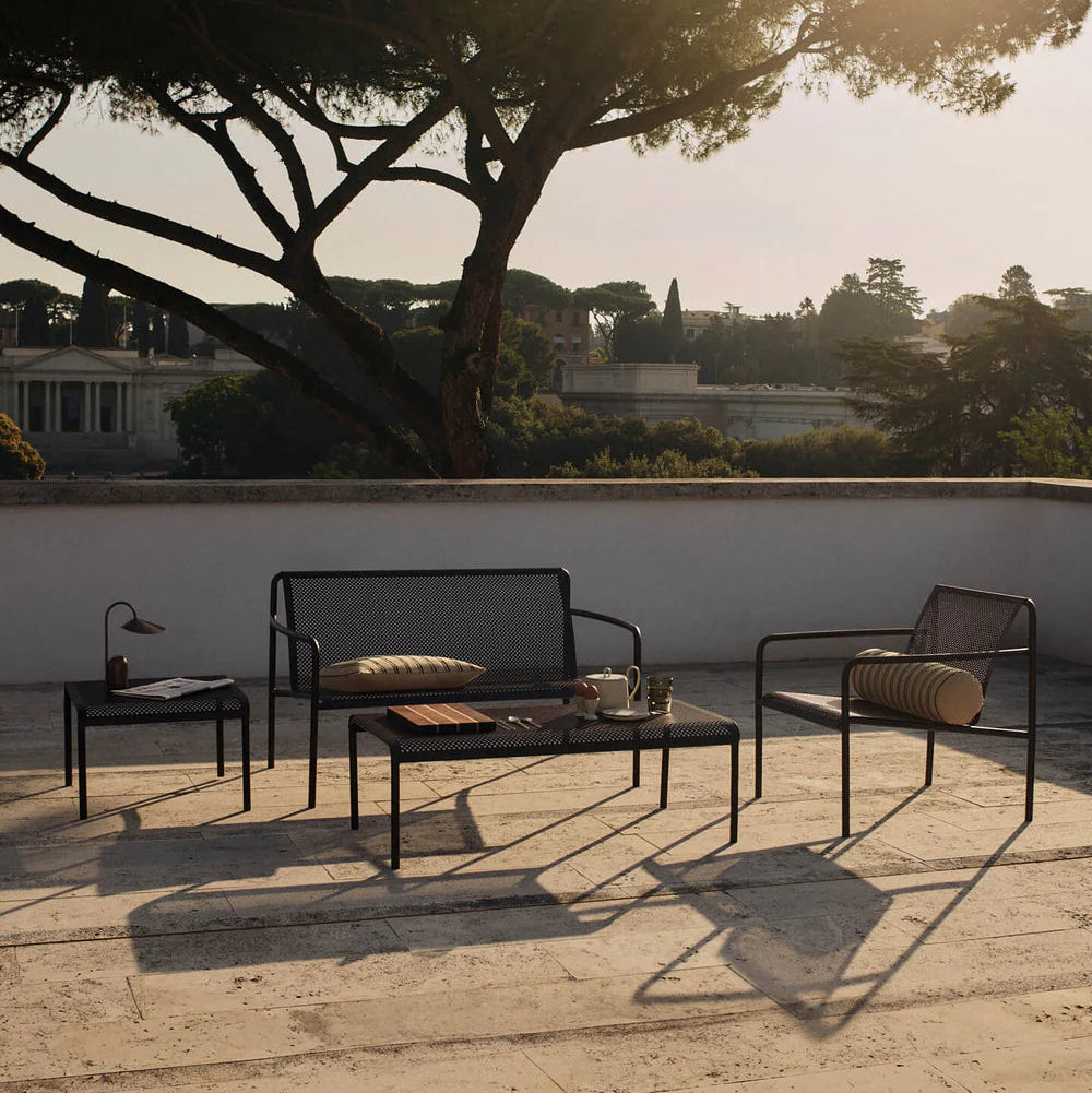 Outdoor patio set with furniture on a stone patio, sunlit by a large tree.