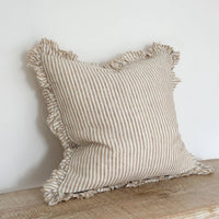 Thumbnail for Striped linen pillow with ruffled edges on a wooden surface against a white wall