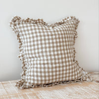 Thumbnail for Checkered pillow with ruffled edges on a wooden surface against a white wall