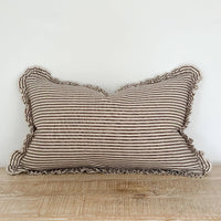 Thumbnail for Striped pillow with ruffled edges on a wooden surface against a white wall