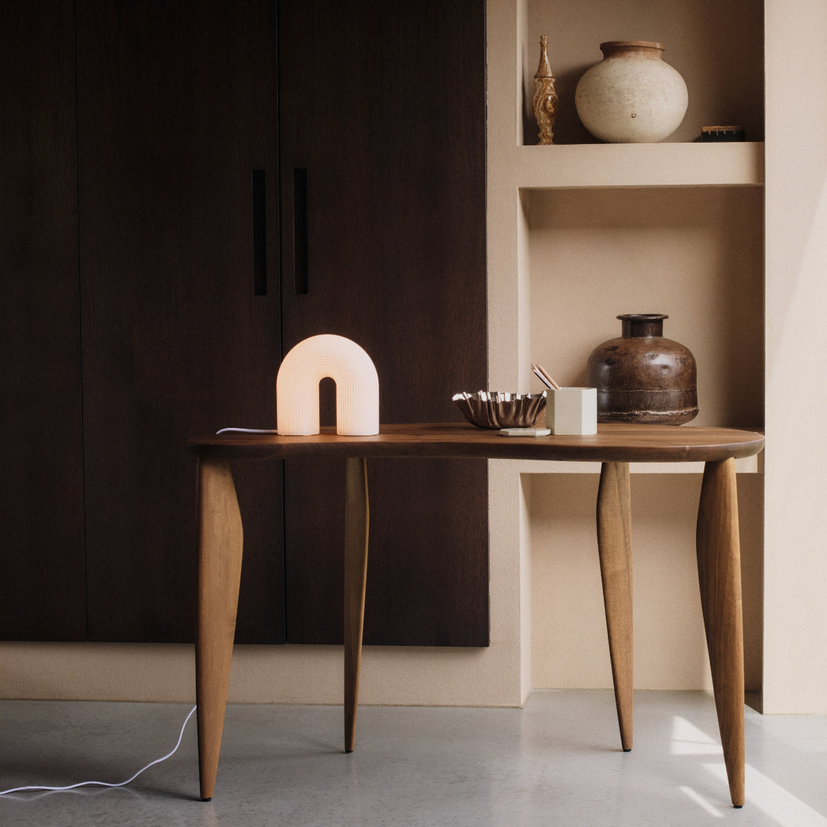 Arch-shaped lamp on a wooden surface with a dark background