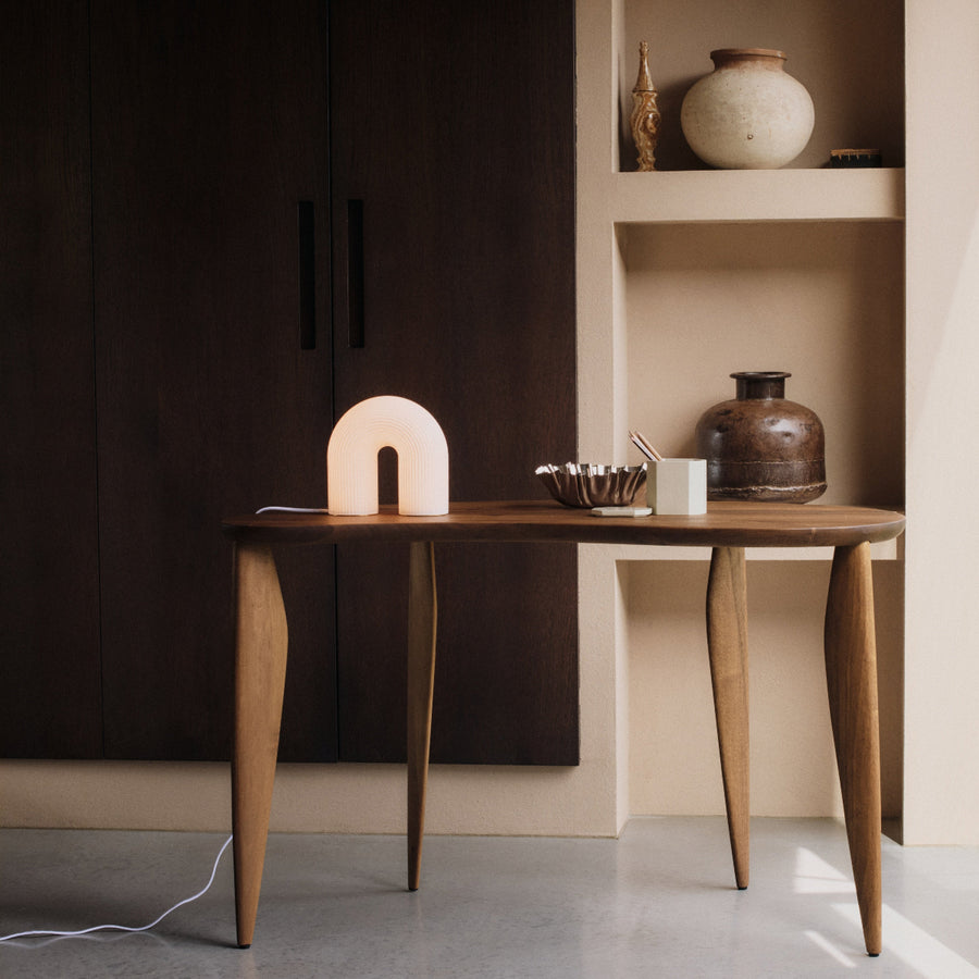 Arch-shaped lamp on a wooden surface with a dark background