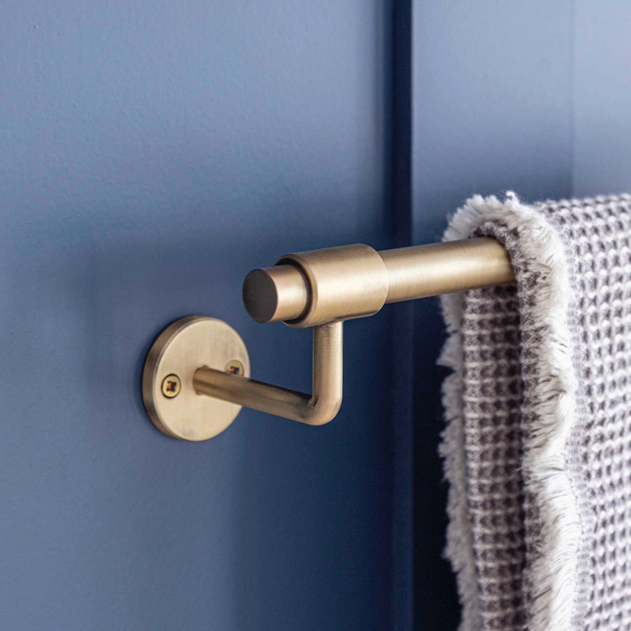Gold towel rack with a gray towel against a blue wall