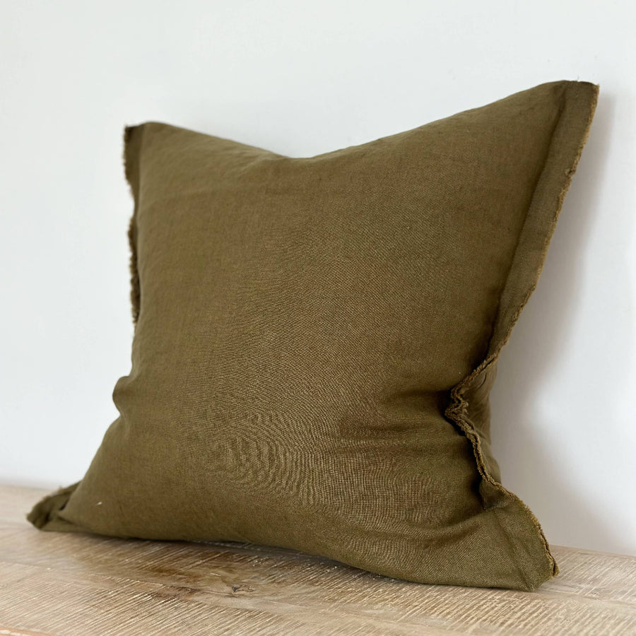 Green Linenpillow on a wooden surface with a white background