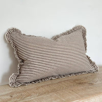 Thumbnail for Striped pillow with ruffled edges on a wooden surface against a white wall