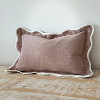 Thumbnail for Brown pillow with white trim on a wooden surface against a light gray wall