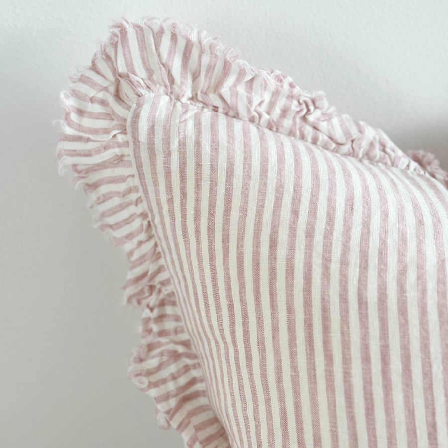 Pink striped pillow with ruffled edge on a light gray background