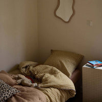 Thumbnail for Bed with checkered blanket and pillows in a room with a mirror on the wall.