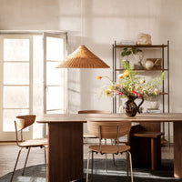 Thumbnail for Ferm Living Dining area with wooden table, chairs, and a vase of flowers in a softly lit room.