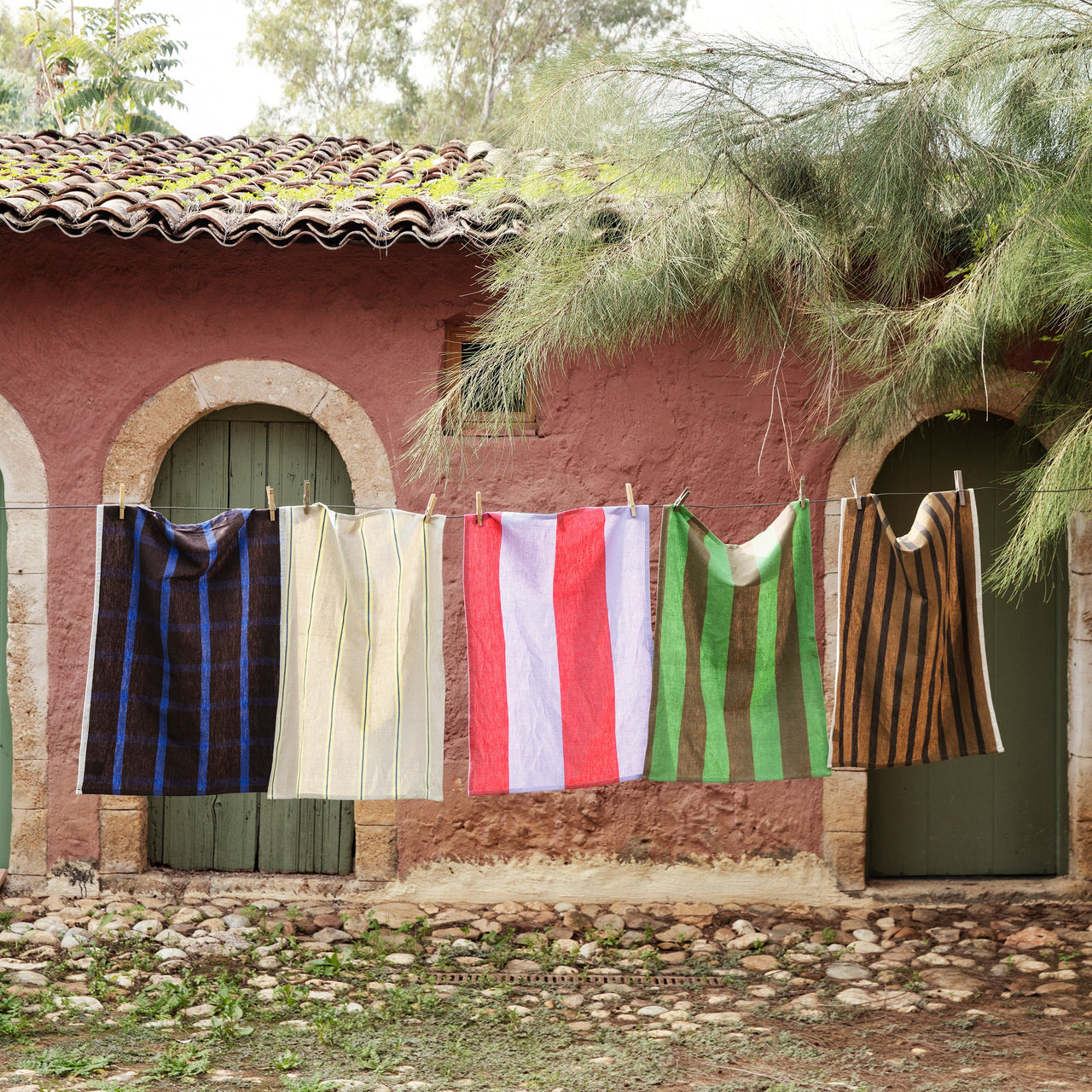 Colorful cloths hanging on a line outside a rustic building with greenery.