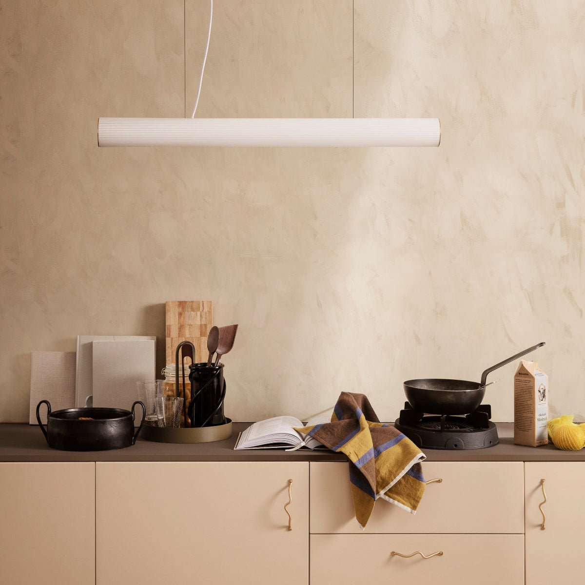 Beige kitchen with pendant light and various items on the counter