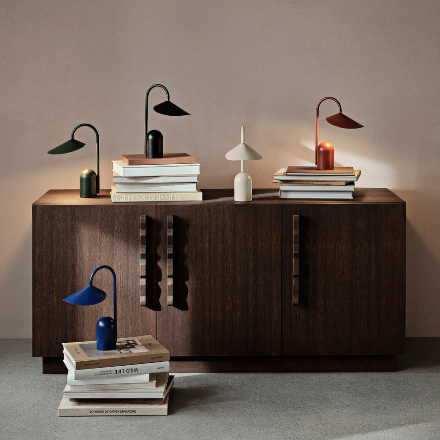 Dark wooden sideboard with decorative lamps and books against a plain wall.
