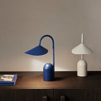 Thumbnail for Blue table lamp and white candle-style lamp on a wooden surface with a neutral background