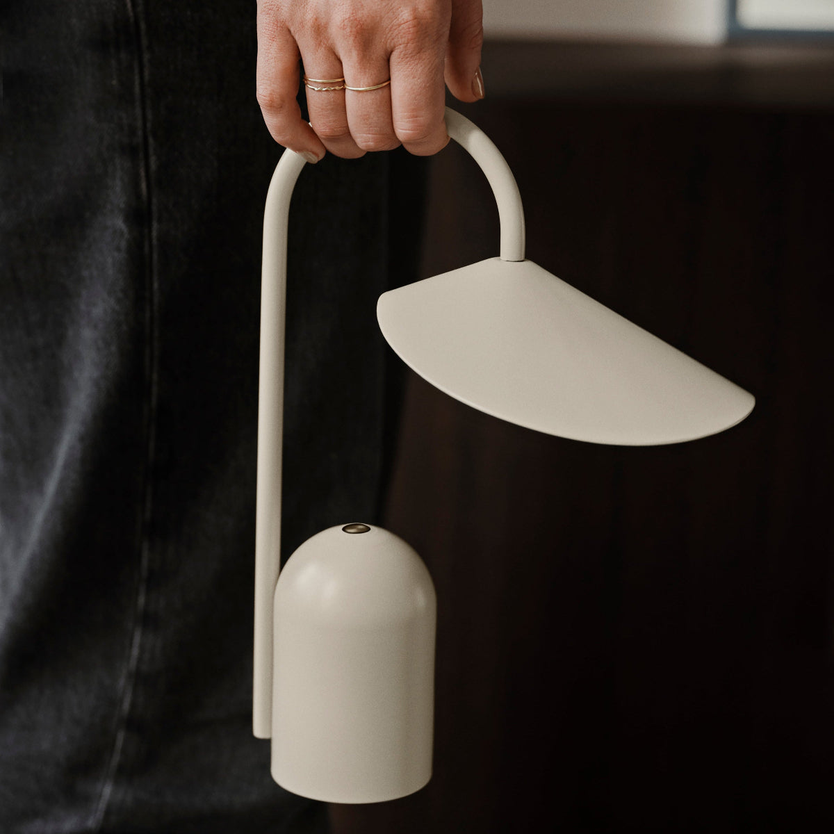 Person holding a modern white lamp with a curved design.