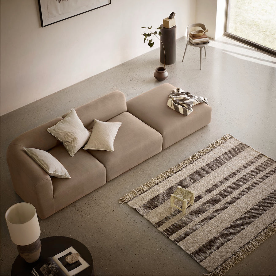 Beige sofa in a modern living room with a striped rug and minimal decor.