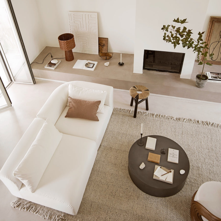 Modern living room with a white sofa, round coffee table, and fireplace.