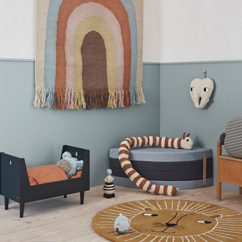 oyoy living design mini collection with lion rug, rainbow wall hanging, brown and white snake toy cot and tooth fairy on the wall.